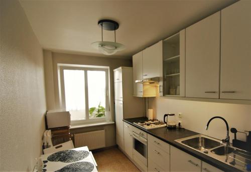 d'une cuisine avec des placards blancs, un évier et une fenêtre. dans l'établissement Oh-la-laa, à Ventspils