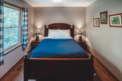 a bedroom with a bed with a blue comforter and a window at Patriot Cottage at American Heartland Cabins in Rockbridge