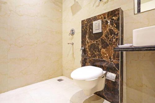 ein Bad mit einem WC und einer Marmorwand in der Unterkunft Iconic Stay Delhi Airport in Neu-Delhi