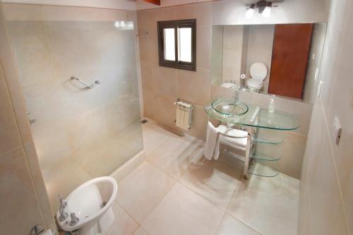 ein Badezimmer mit einem Glaswaschbecken und einem WC in der Unterkunft Hostal La Merced in Villa General Belgrano