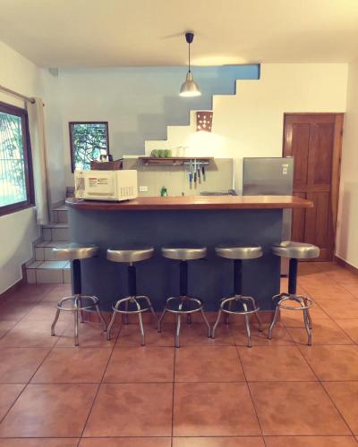 a kitchen with a counter and stools in a room at Villas Macondo in Tamarindo