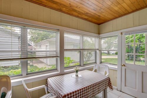 a screened in porch with a table and chairs and windows at Historic Home with Sunroom - 5 Mi to Lambeau Field! in De Pere