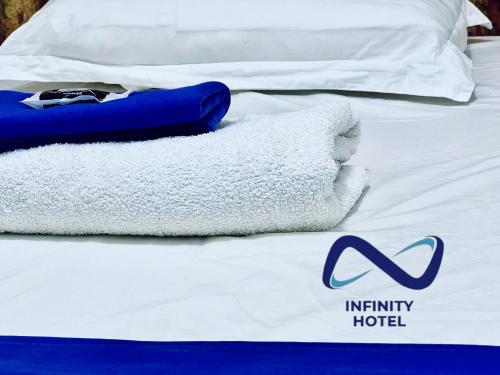 a bed with white sheets and towels on it at Infinity Hotel Kampala in Kampala