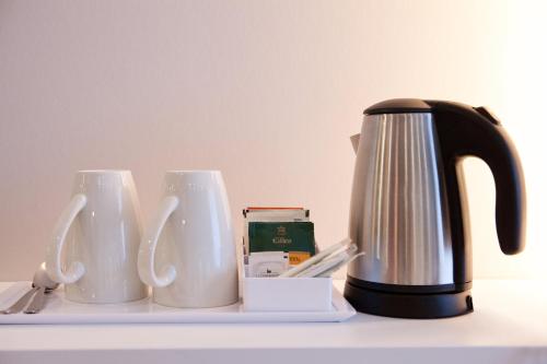 a coffee pot and two cups on a table at Holiday Inn Express Munich - Olympiapark by IHG in Munich