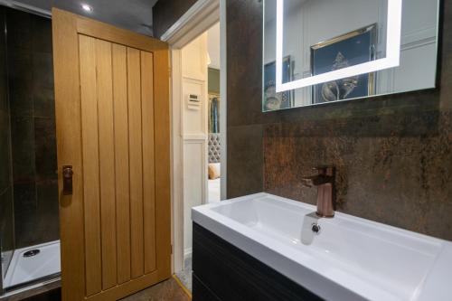 a bathroom with a white sink and a wooden door at The Lower Buck Inn in Clitheroe