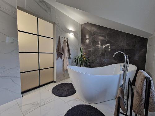 a bathroom with a white tub and a black wall at Seliu 25 Homestay Apartment poilsio namai in Šiauliai