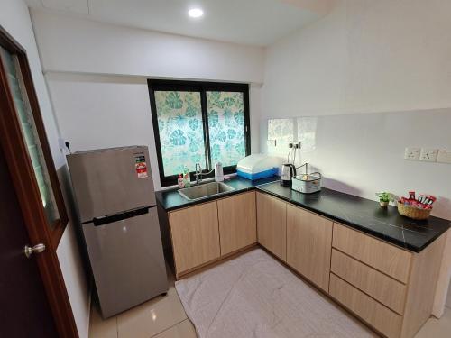 La cuisine est équipée d'un réfrigérateur et d'un évier. dans l'établissement Cozy 2room 7pax, Menara Sentral, à Bukit Mertajam