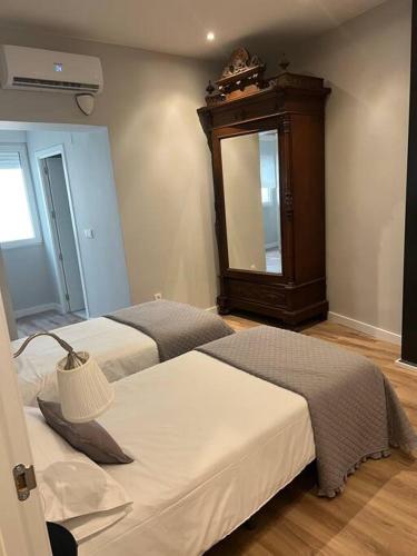 a bedroom with two beds and a dresser and a mirror at Precioso y céntrico apartamento in Zaragoza