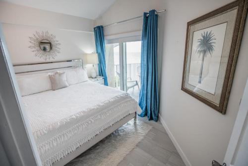 喬治城的住宿－Enjoy Sunsets at Fully Equipped Condo at the Beach，卧室配有白色的床和蓝色窗帘