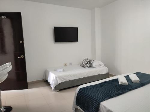 a white room with two beds and a flat screen tv at Loft en San Fernando 106 in Cali