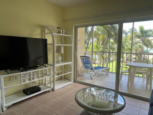 a living room with a flat screen tv and a balcony at #44 Plantation Village in George Town