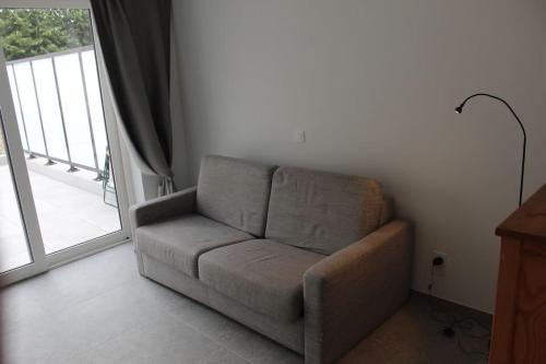 a couch sitting in a living room next to a window at Ruim nieuwbouwappartement oostduinkerke in Oostduinkerke
