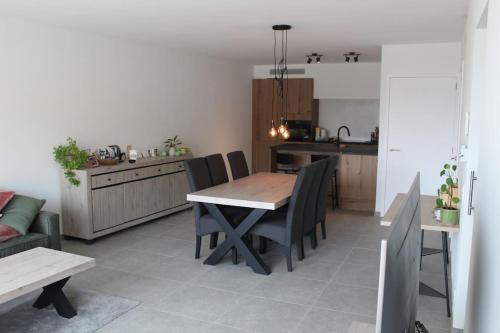 cocina y comedor con mesa y sillas en Ruim nieuwbouwappartement oostduinkerke, en Oostduinkerke