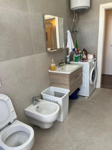 a bathroom with a toilet and a sink and a washing machine at Lukas Apartament Vollga Durres in Durrës