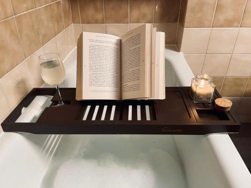 un livre et un verre de vin sur une étagère dans une baignoire dans l'établissement Le Fauriel - Parking gratuit - Centre ville, à Saint-Étienne