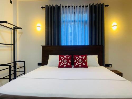 Un dormitorio con una cama con almohadas rojas y una ventana en Thanu Villa en Unawatuna