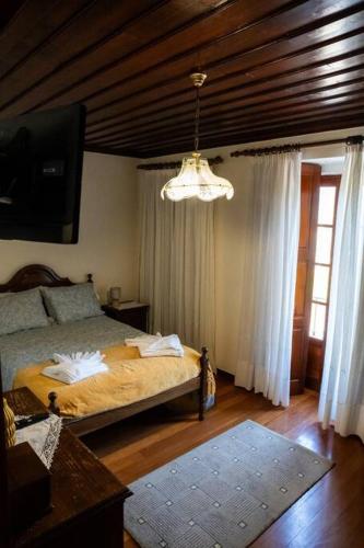 a bedroom with a bed and a chandelier at Refúgio dos 3 Passos in Lanhas