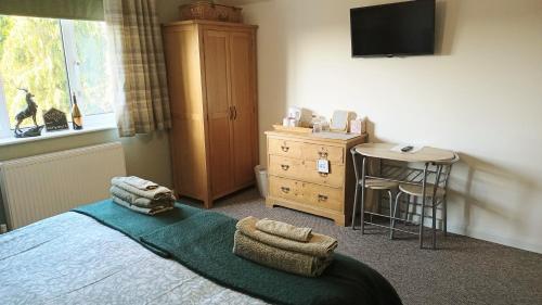 Schlafzimmer mit einem Bett, einem Schreibtisch und einem TV in der Unterkunft Bowtree House Bed and Breakfast in Grantham