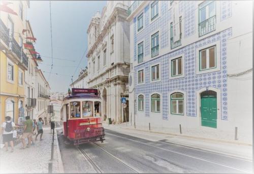 a red tram on a city street with buildings at Lisbon House Misericordia in Lisbon