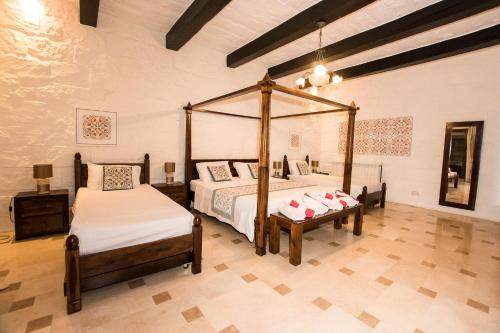 una camera con 2 letti e un letto a baldacchino di Il-Bejta Farmhouse a Għarb