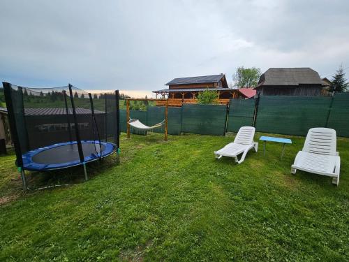 a backyard with a trampoline and two chairs at Cabana Refugiul Montan Belis in Beliş