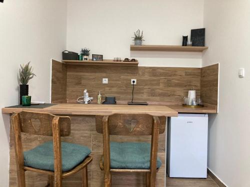 eine Küche mit einer Holztheke mit Stühlen und einem Kühlschrank in der Unterkunft Aurora Apartment in Kikinda