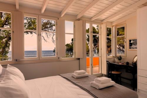 sypialnia z oknami, łóżkiem i biurkiem w obiekcie Melissi 1932 - Seaside villa w mieście Melíssion