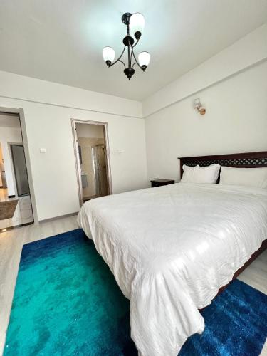 a bedroom with a large white bed with a blue rug at Lovely 2bedroom Apartment overlooking Nairobi City in Nairobi