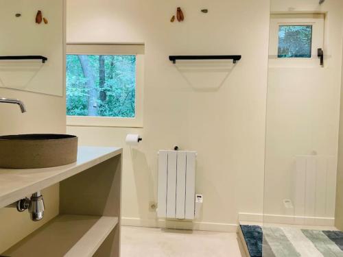 a white bathroom with a sink and a window at Prachtige chalet in het bos met sauna! in Lanaken