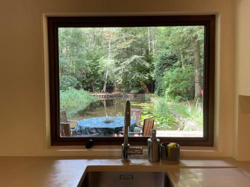 a kitchen sink with a window looking out at a table at Prachtige chalet in het bos met sauna! in Lanaken