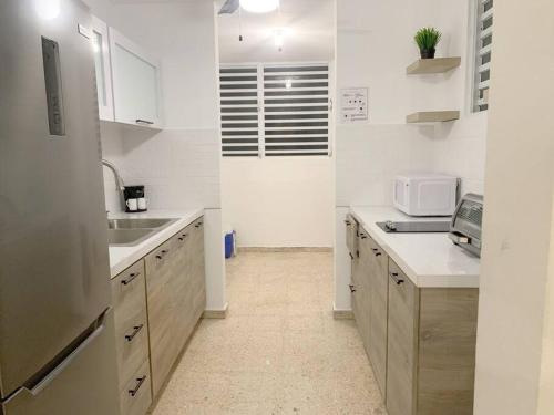 a kitchen with white cabinets and a sink and a microwave at Villa del Sol in Luquillo