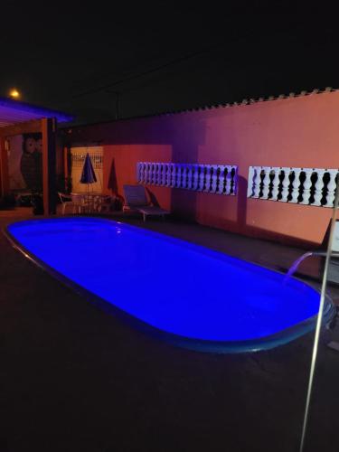 a large blue swimming pool in a room at night at Pousada das Artes 2 in Mongaguá