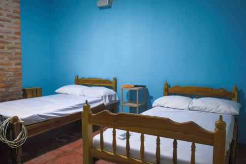 - 2 lits dans une chambre avec un mur bleu dans l'établissement VILLA LAS FLORES, à La Libertad