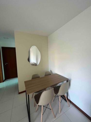 a dining room table with three chairs and a mirror at Apto acolhedor na Passagem in Cabo Frio