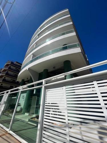 a tall building with a glass facade with a blue sky at Apto acolhedor na Passagem in Cabo Frio
