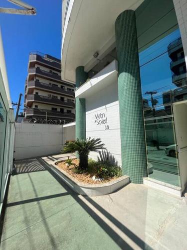 a building with a green pillar in front of a building at Apto acolhedor na Passagem in Cabo Frio