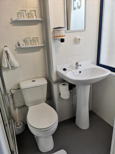 a white bathroom with a toilet and a sink at Hostel de las Facultades in Santander