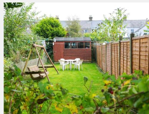 a garden with a swing and a table and chairs at Fishermen Cottage - 5 star location- 90sq garden -2 living room- 2 bath room -pets friendly -comfortably sleep 5-6 people -50 percent off monthly -self check in in Deal
