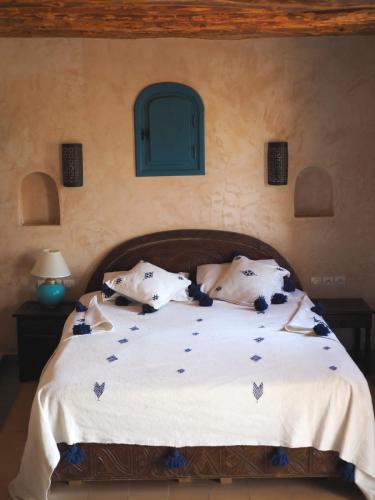 a bedroom with a bed with white sheets and pillows at Paradis Nomade in Azrarag