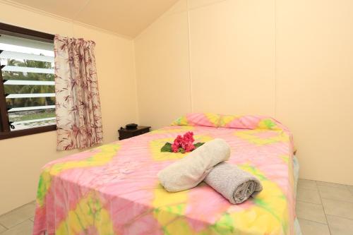 Una cama con dos toallas y una flor. en Ranginui Sunset, en Arutanga