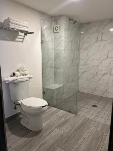 a bathroom with a toilet and a glass shower at Hotel Bugambilia in Hermosillo