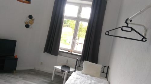 1 dormitorio con cama, ventana y silla en Stella s Monteurswohnungen en Crimmitschau