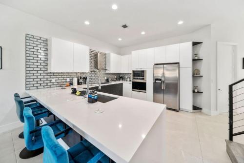a kitchen with a large white counter and blue chairs at Modern RocknHome Near Hard Rock and FLL Airport in Fort Lauderdale
