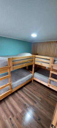 two bunk beds in a room with wooden floors at Cabaña Ailin in Curacautín