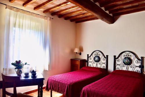 een slaapkamer met 2 bedden met rode lakens en een raam bij Relax in Chianti IL BORGO 7 in Montespertoli