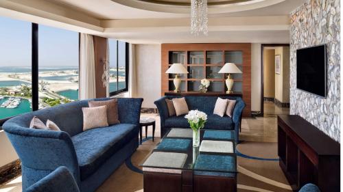 a living room with blue couches and a tv at InterContinental Abu Dhabi by IHG in Abu Dhabi