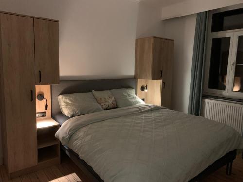 a bedroom with a large bed and a cabinet at De zwarte deur in Genk