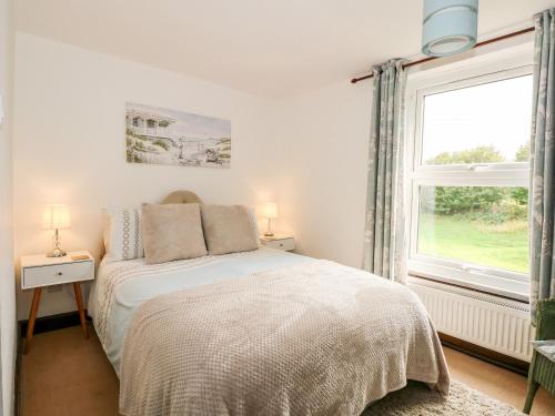 a white bedroom with a bed and a window at Kathy's Cottage in Kings Lynn