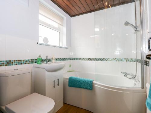 金斯林的住宿－Kathy's Cottage，白色的浴室设有浴缸、卫生间和水槽。