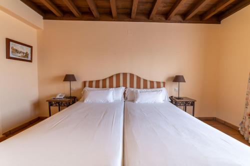 a bedroom with a large bed with two tables at Cigarral de Caravantes in Toledo